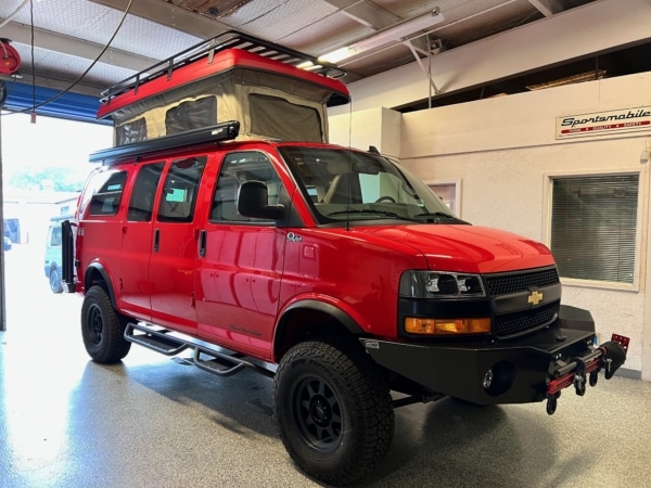 Red Chevrolet Express with popped up roof parked in the garege.