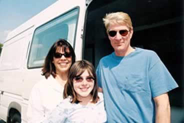 Photo of a happy family of three in front of their new converted van.